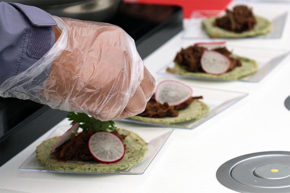 Image shows a hand adding garnish to small plates of food