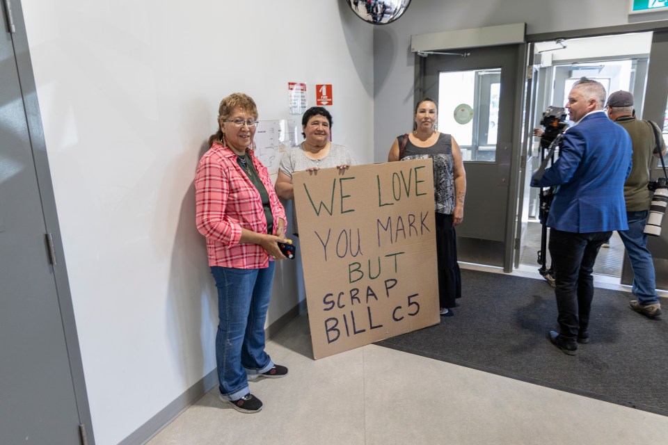 Connie Benwell, centre, holds a placard urging the prime minister to scrap Bill C-5, the recently passed legislation that promotes nation-building projects. "It's infringing on our treaty rights and not consulting with the Aboriginal people on major decisions," Benwell told Cabin Radio. "We were here first. We were put here to look after our lands, look after our water. This is what we are doing and we will stand by it." Ollie Williams/Cabin Radio