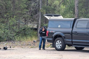 A police officer sets up a drone during an RCMP operation on July 11, 2025. Sarah Pruys/Cabin Radio