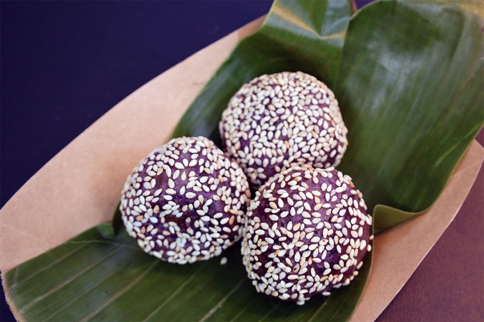 Trio of sesame balls covered with sesame seeds, laying on a banana leaf.