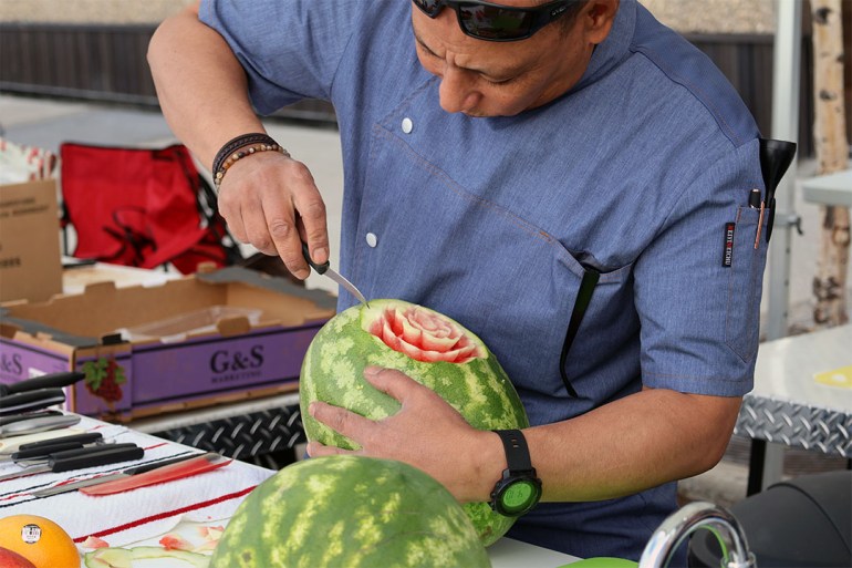 Chef demonstrates carving decorative patterns in a watermelon.
