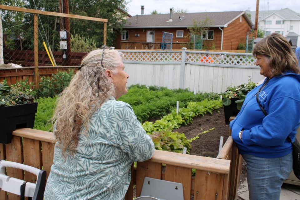 Laity (left) talking about her carrots, lettuce, peas and tomato plants. - Sara Verheul/Cabin Radio