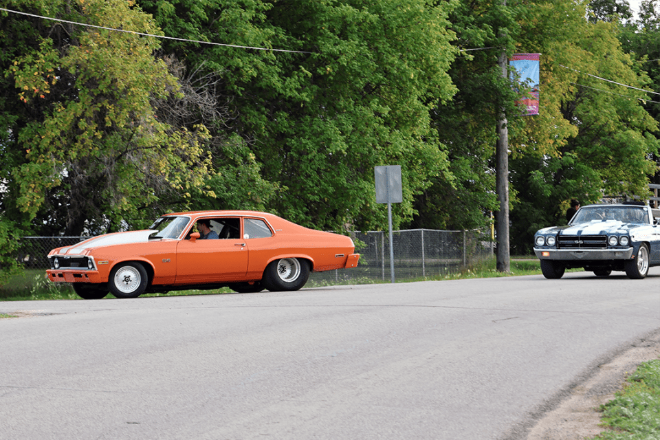 Two vintage cars drive in a parade