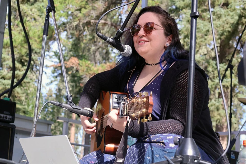 Woman with guitar sits on stage