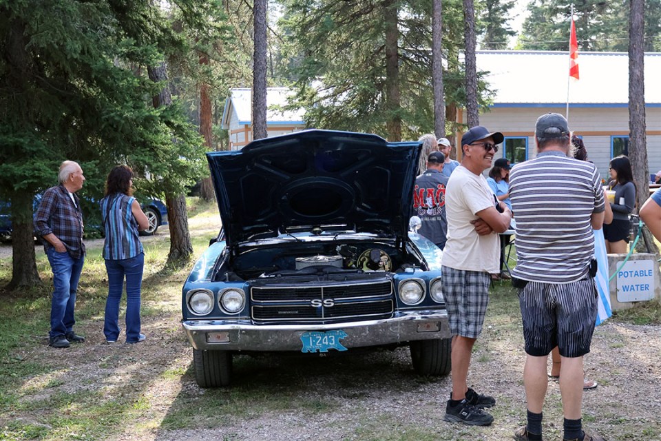 Vintage car with hood open surrounded by waiting crowd