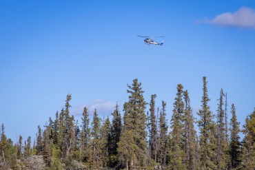 A helicopter with a bucket over Tin Can Hill on September 1, 2025. Ollie Williams/Cabin Radio