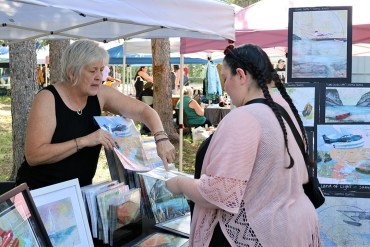 A vendor shows a woman her art.