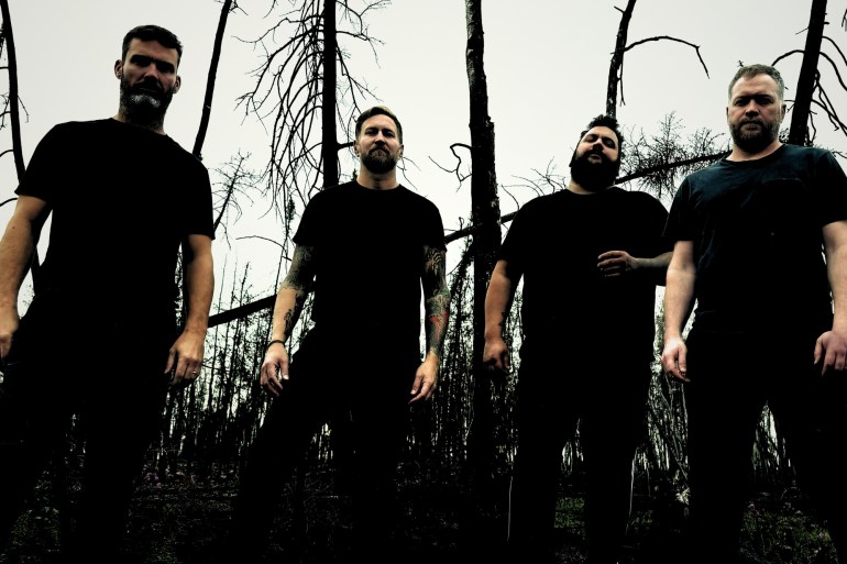 4 band members standing in front of trees