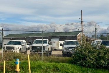 Smoke from fire FS014 is seen behind a wildfire operations compound in Fort Simpson. Photo: Lynn Canney