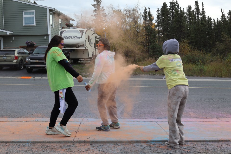 Runners are doused in colour at a colour station partway through the run. Aastha Sethi/Cabin Radio
