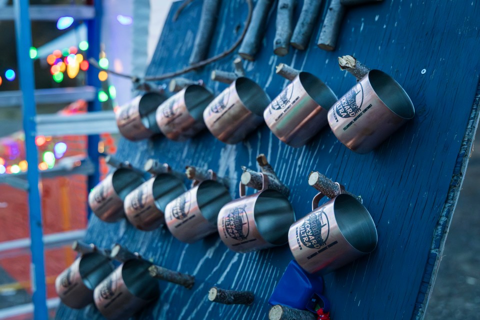 Commemorative mugs hang at the finish line. When you tap out, take a mug with you. Ollie Williams/Cabin Radio