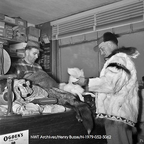 Trapper and prospector Sam Otto, right, trades furs with Bruce Weaver at Weaver and Devore on Christmas Eve 1953. NWT Archives/Henry Busse fonds/N-1979-052: 5062