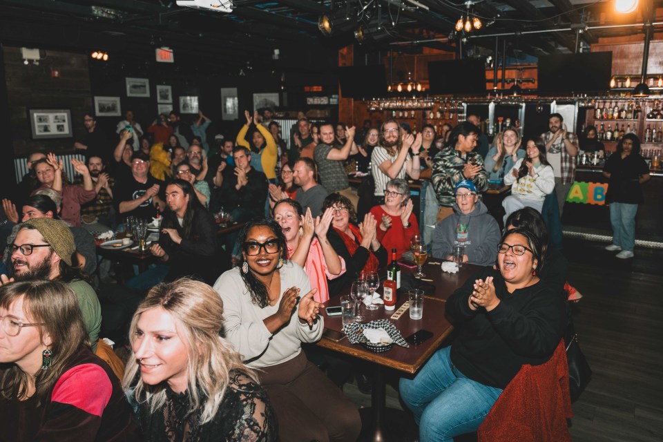 The crowd cheers as Jacki McKinnon spells the championship word – Deninu Kųę́, without the accents – properly to win the game. Sarah Pruys/Cabin Radio
