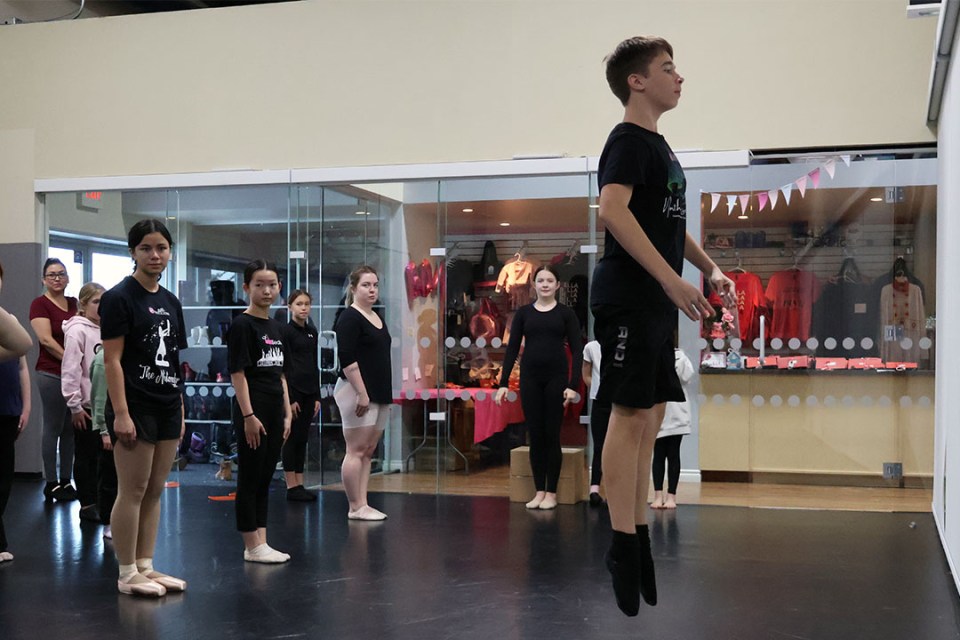 Teenage boy practices a jump during a rehearsal for a ballet