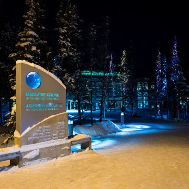 Illuminated trees on the walkway to the NWT legislature. Ollie Williams/Cabin Radio