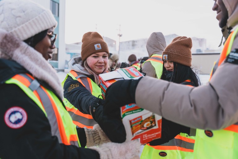 Non-perishable donations cross Franklin Avenue with the help of high school students. Sarah Pruys/Cabin Radio
