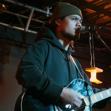 Man plays guitar and sings into a microphone