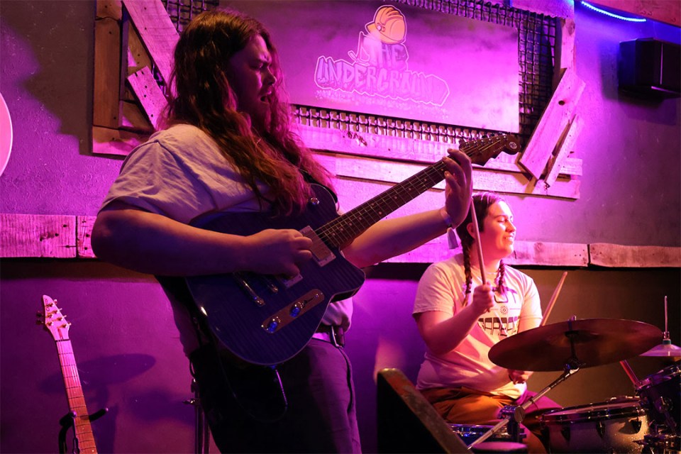 Members of HYFY play guitar and drums on stage