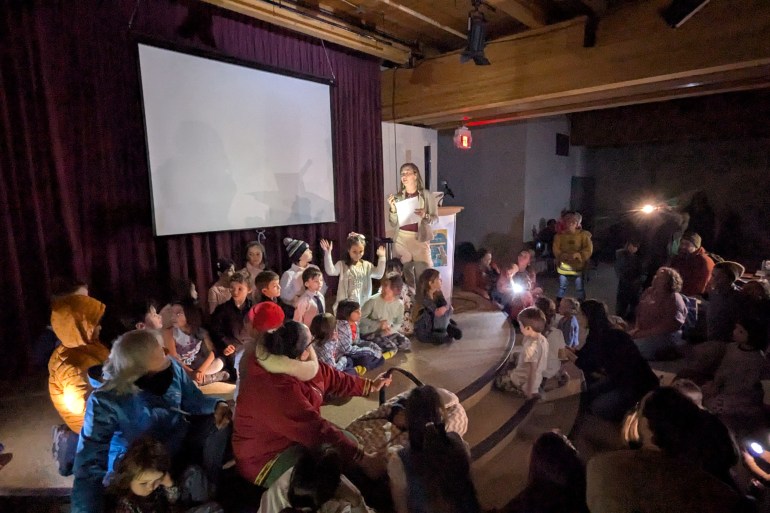 Despite the loss of electricity, Mildred Hall School teacher Ashley Deavu congratulates her young students on their scrap paper creations of Ice Age critters. Photo: Bill Braden