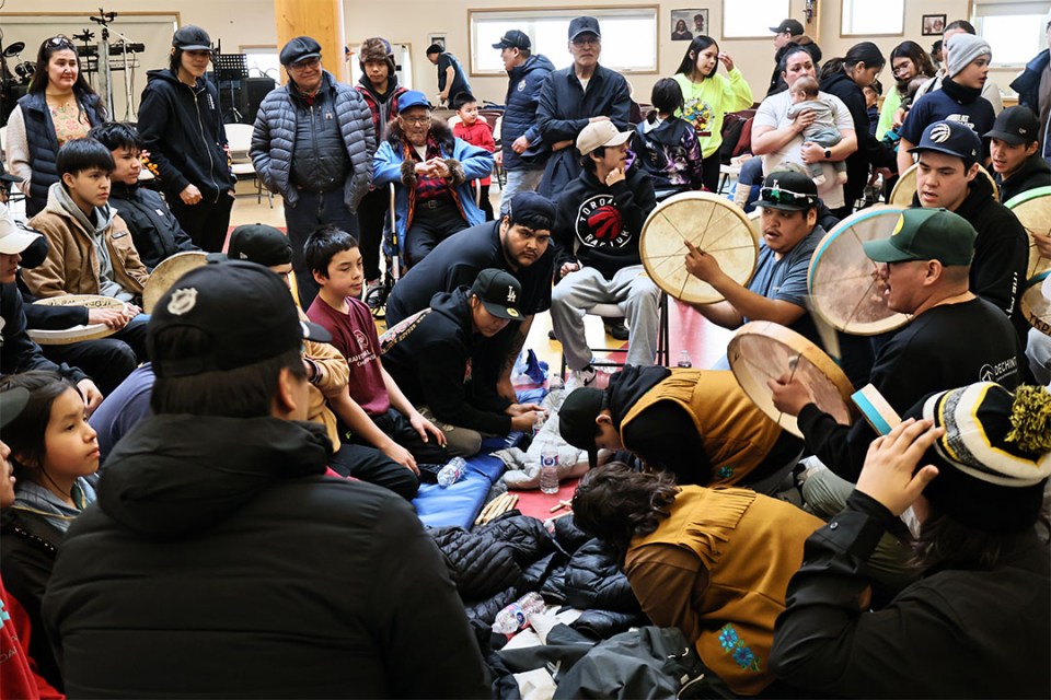 Group of people stand around kneeling competitors in hand games.