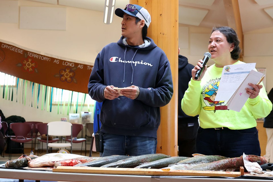 A man and a woman stand in front of a table of caught fish