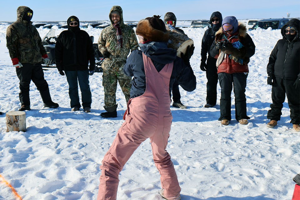 Woman holding a stump gets ready to throw it as far as she can.