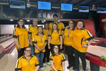 NWT bowlers pose with their medals in front of bowling lanes at the King Pin Bolwing Centre