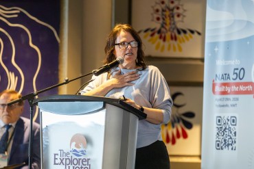 NWT Tourism's Donna Lee Demarcke speaks at the Northern Air Transport Association's conference in Yellowknife in late April 2026. Ollie Williams/Cabin Radio