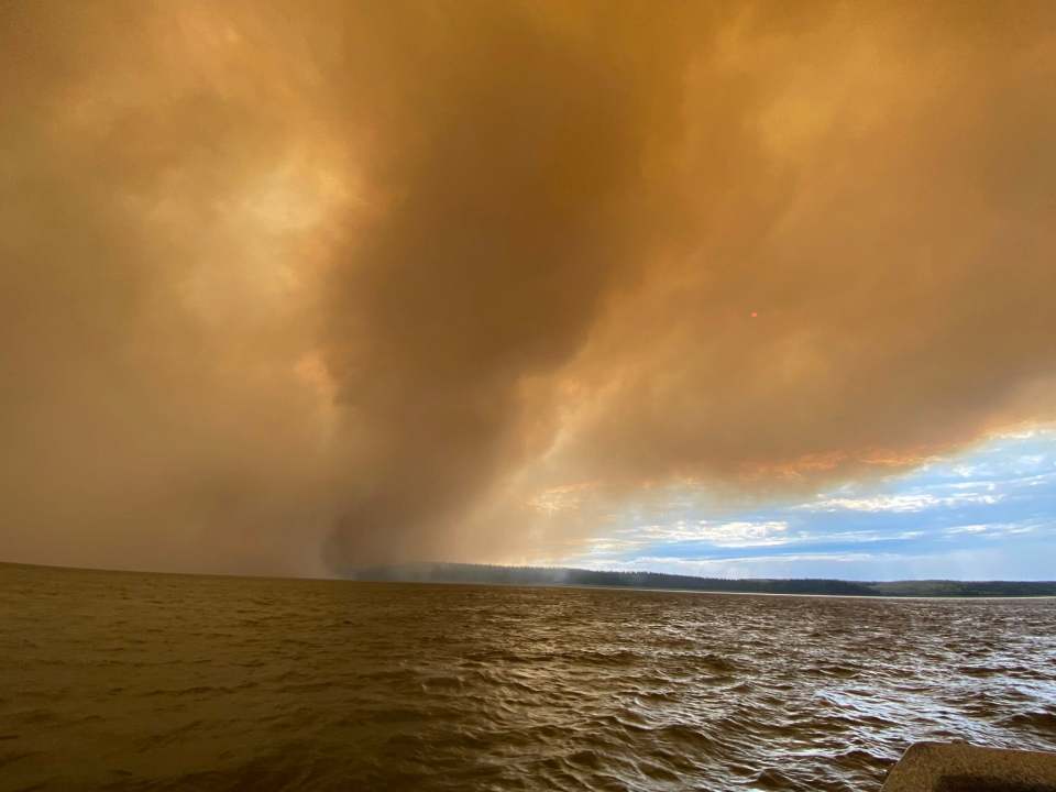Smoke fills the air as evacuees leave Fort Simpson by boat on the evening of June 29, 2026. Photo: Dawn Isaiah