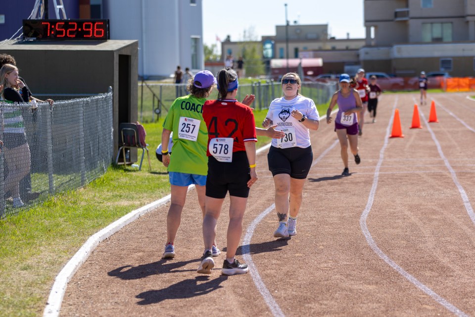 From left: Annie Casson and Jill Gilday congratulate Nikita Hehn at the end of a women's 3,000m race at Track and Field 2026. Ollie Williams/Cabin Radio