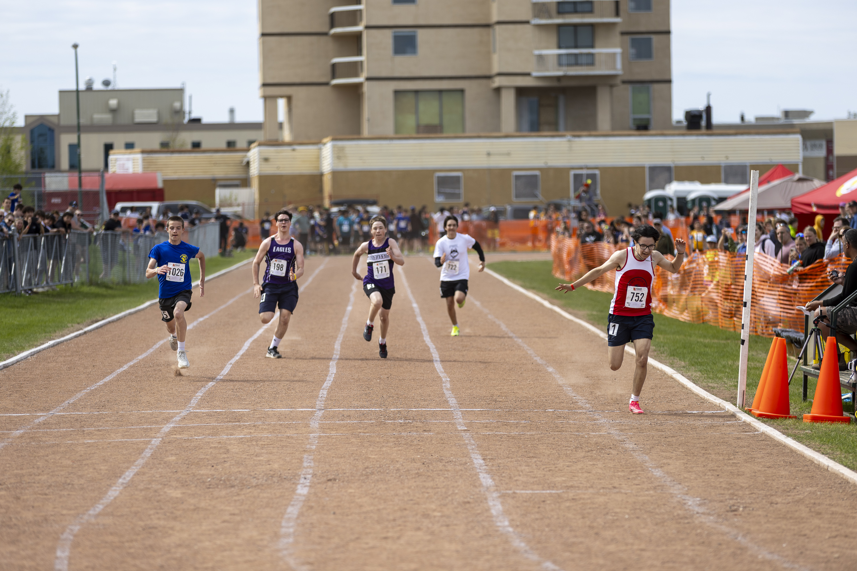 PWK High School's Kyren Poitras, right, ducks at the line during a 100m heat at Track and Field 2026. Ollie Williams/Cabin Radio