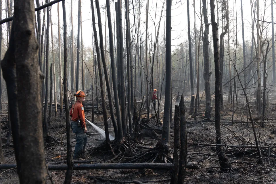 Crews hose down hot spots on the fire line in Fort Simpson. Claire McFarlane/Cabin Radio