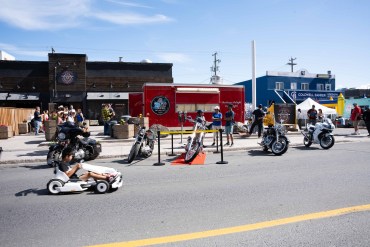 A child on an electric go-kart zooms around on 48 Street at the show and shine. Kai Wilson/Cabin Radio