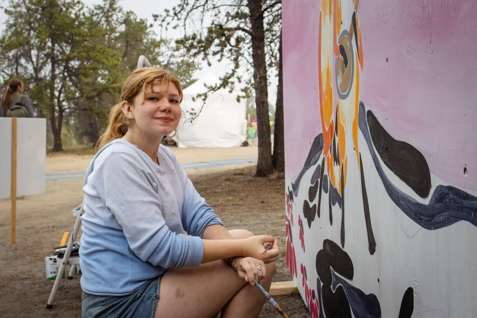 Lisa Weaver paints at Folk on the Rocks 2026. Ollie Williams/Cabin Radio