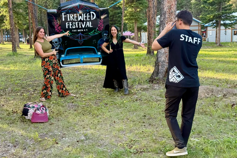 Fireweed Festival visitors pose for a photo in front of a sign in Queen Elizabeth Territorial Park. Ollie Williams/Cabin Radio
