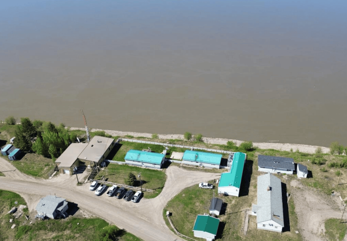 An image from GNWT contract documents shows an aerial view of Fort Good Hope's RCMP compound next to the Mackenzie River.
