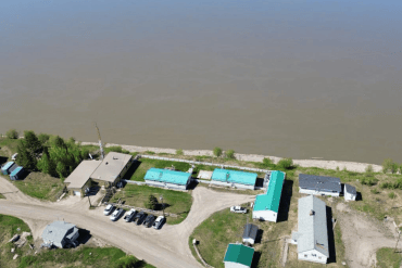 An image from GNWT contract documents shows an aerial view of Fort Good Hope's RCMP compound next to the Mackenzie River.
