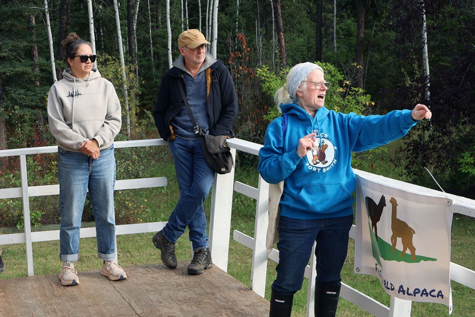 A woman gestures to something behind her while onlookers listen